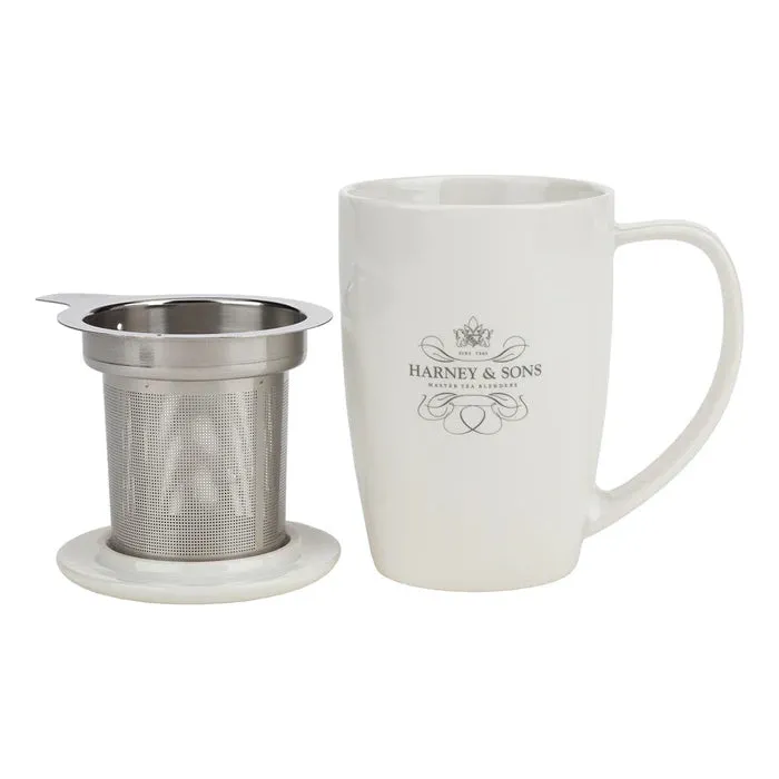 White mug with a metal tea infuser and saucer