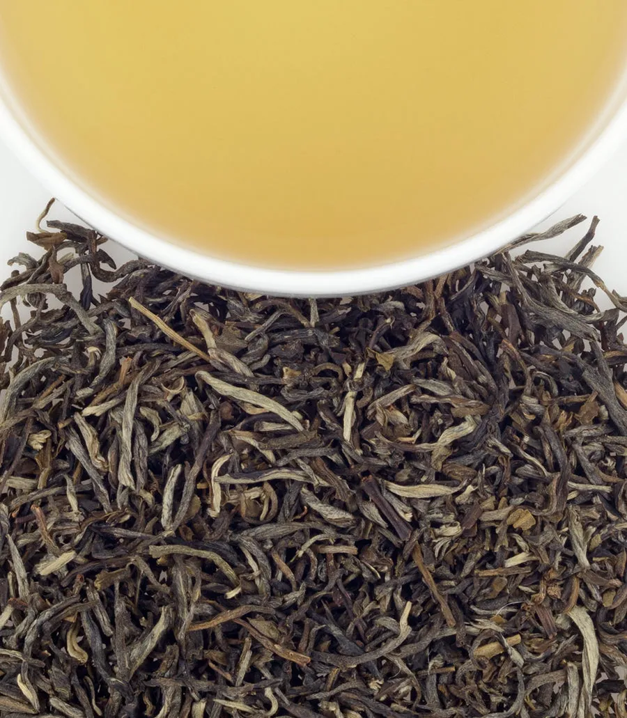 Jasmine tea sachets in a bag of 50, with brewed tea in a cup above loose tea leaves.