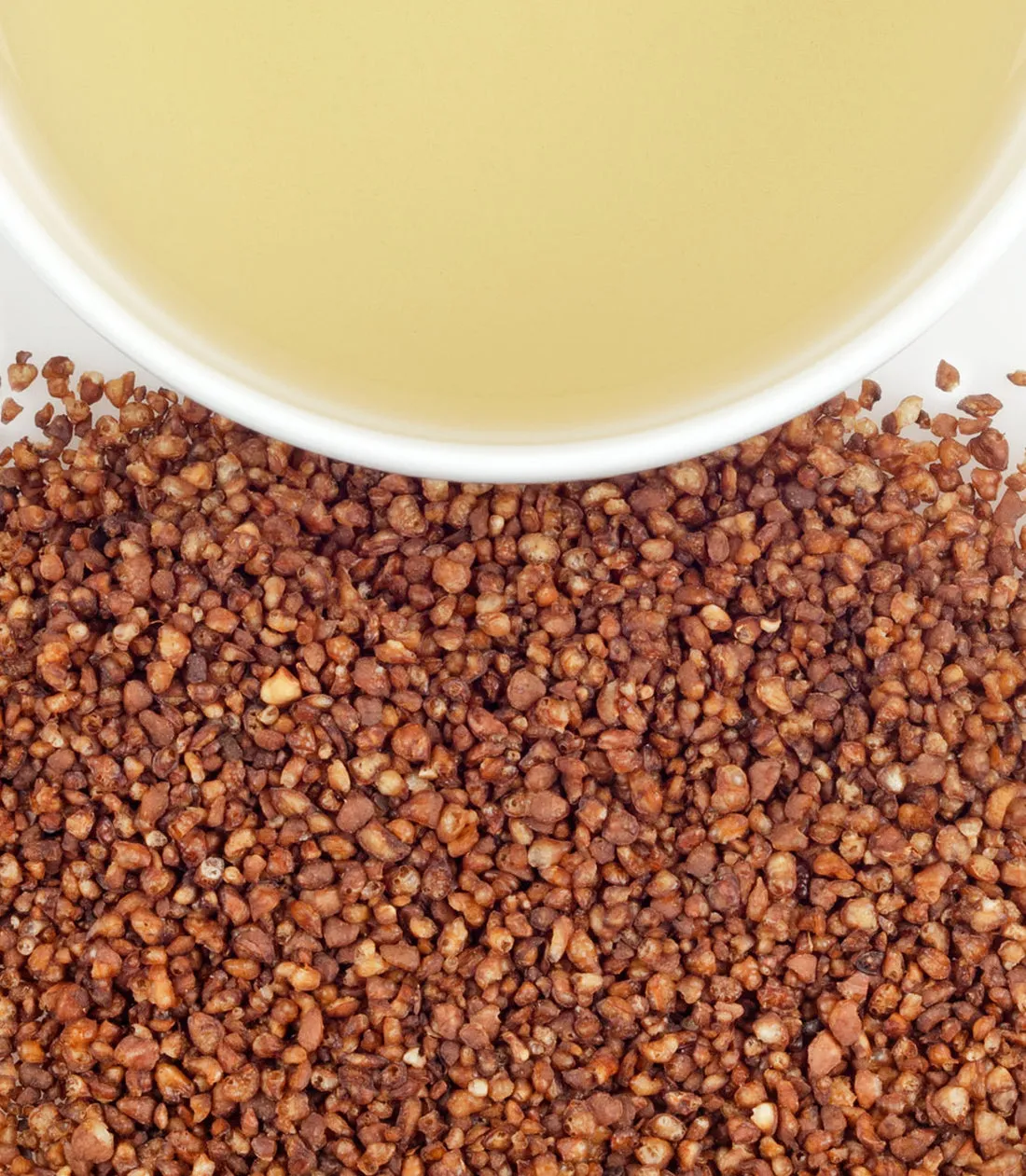 Soba roasted buckwheat grains scattered beside a bowl of light-colored liquid.
