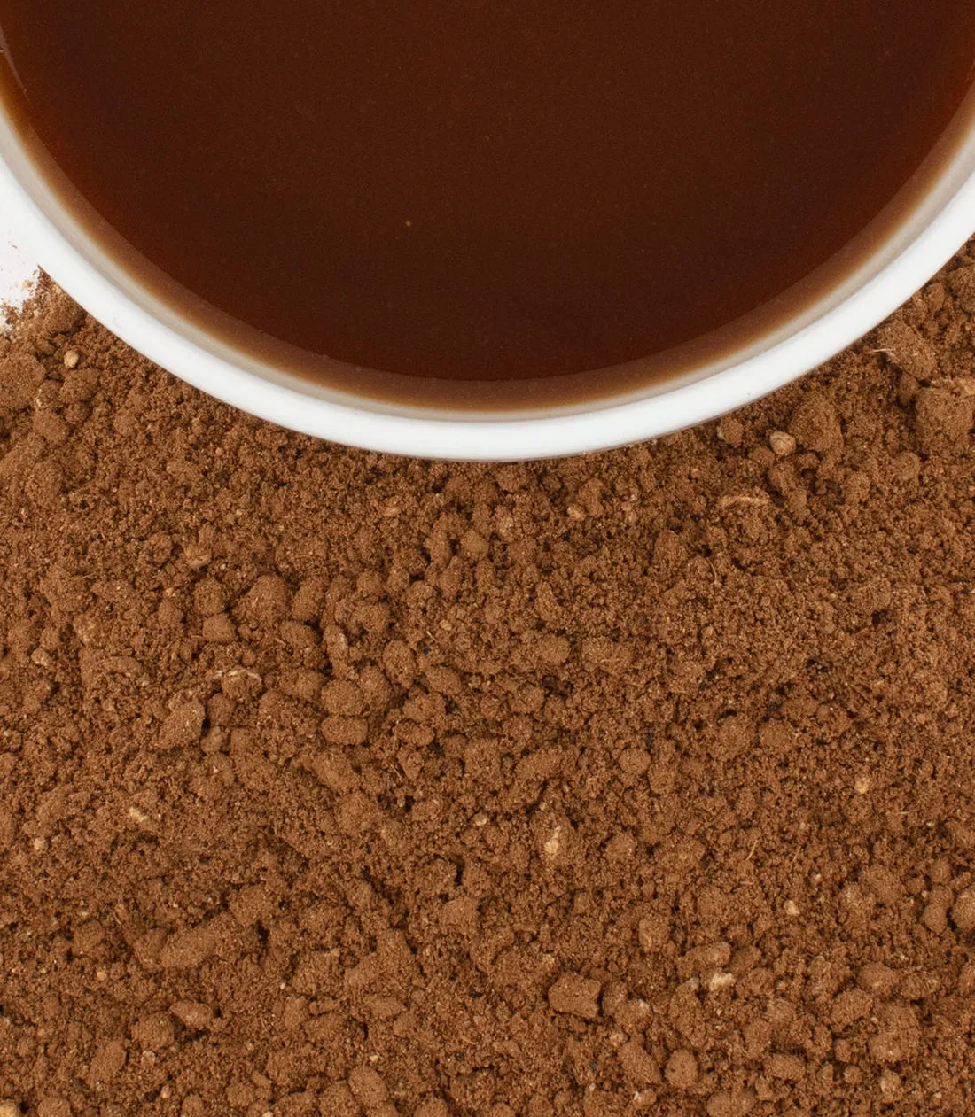 A cup of organic Chaga Chai tea surrounded by loose chai powder.